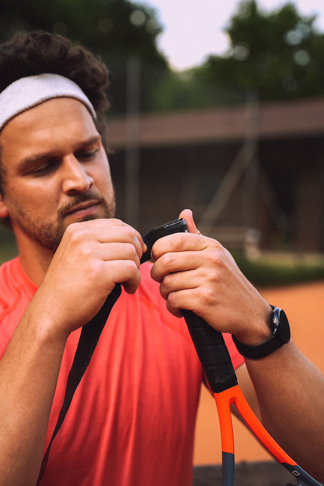 Ein Tennisspieler beginnt einen Overgrip auf seinen Tennisschläger zu wickeln.