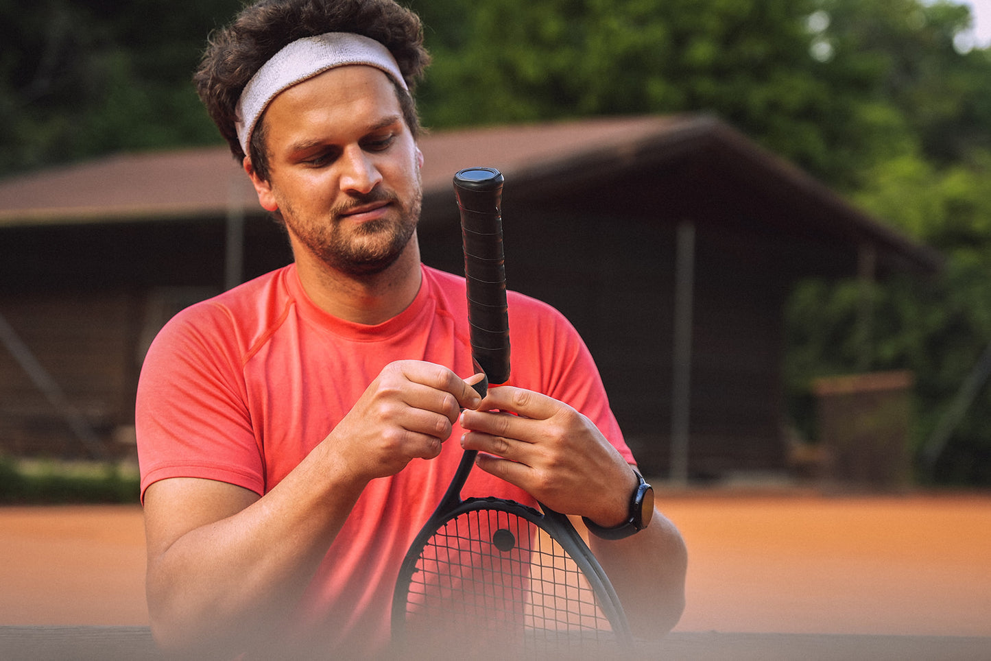 Ein Tennisspieler hat einen neuen Overgrip um den Griff seines Tennisschlägers gewickelt.